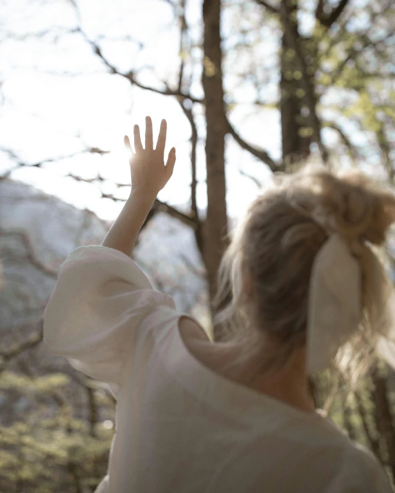 a woman is throwing a frisbee in the air, by Anna Boch, unsplash, naturalism, hands pressed together in bow, albino hair, forest picnic, soft window light