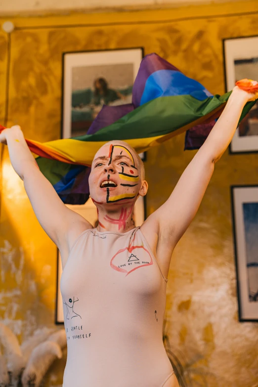 a woman with painted face holding up a rainbow flag, an album cover, by Julia Pishtar, pexels contest winner, feminist art, flag in hands up, making love, sharpie, angelina stroganova