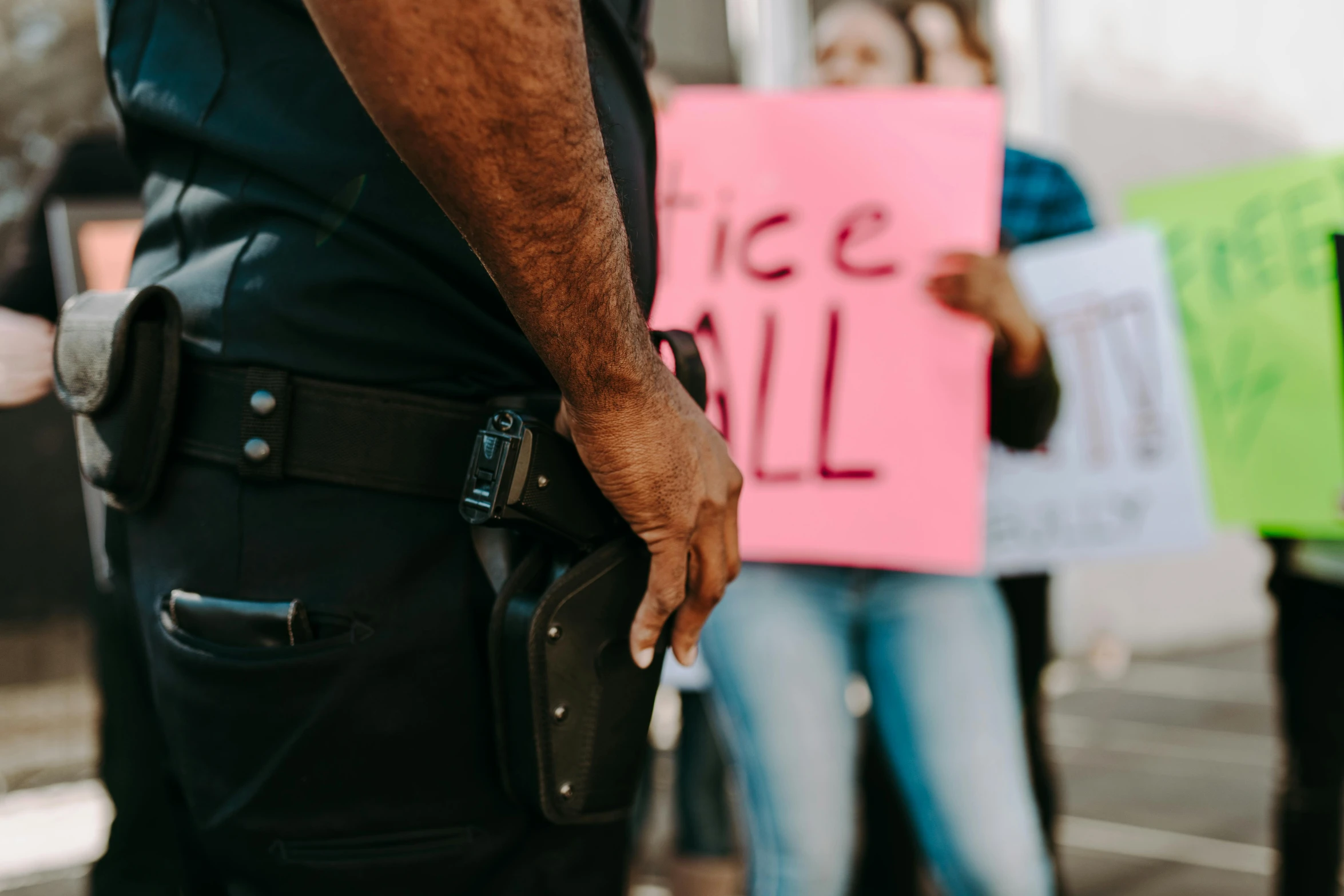 a police officer standing in front of a group of people holding signs, by Carey Morris, trending on pexels, holding handgun, background image, close - up photo, instagram photo