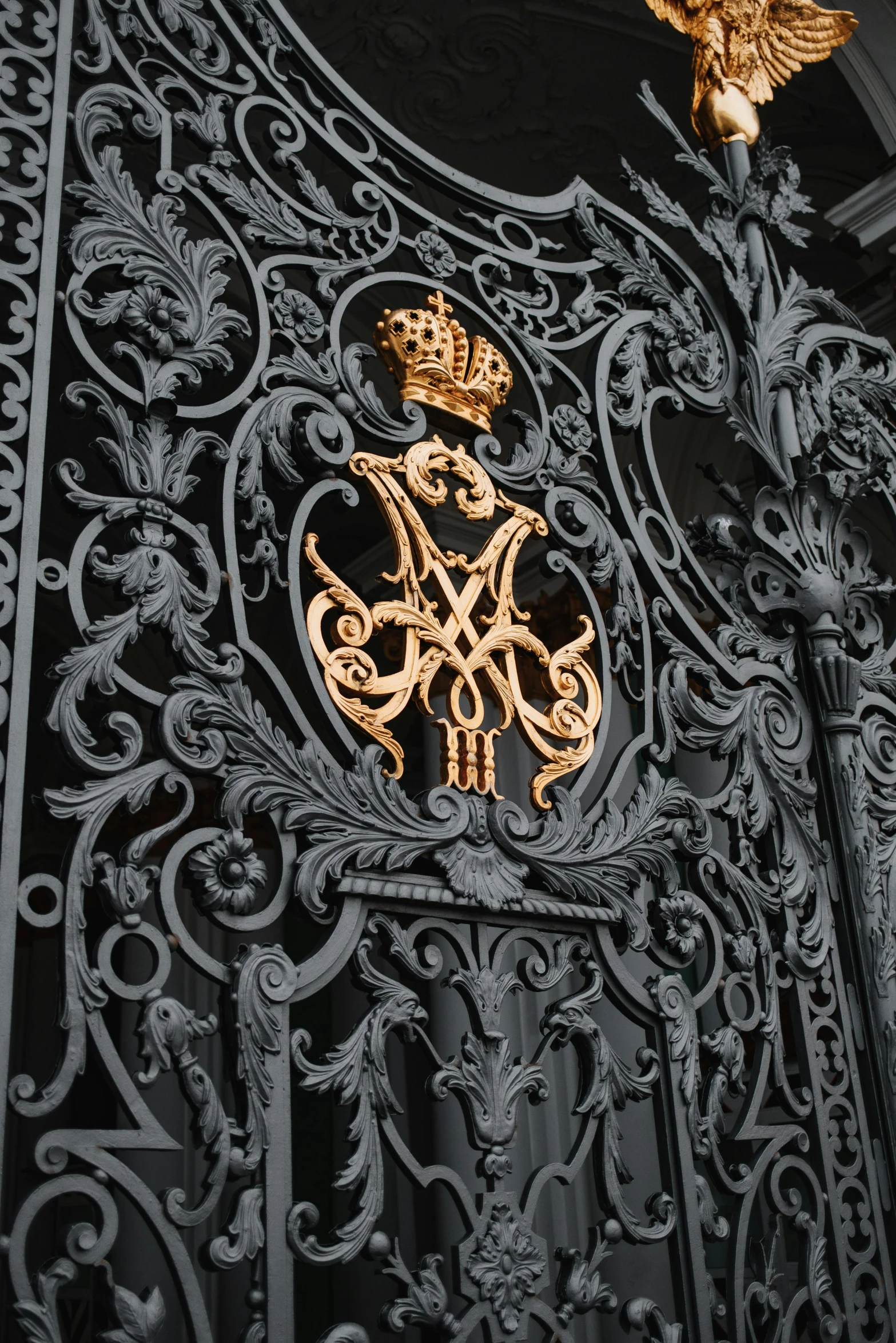 a close up of a metal gate with a crown on it, inspired by Hedi Xandt, baroque, saint petersburg, black and gold palette, intricate writing, coat of arms