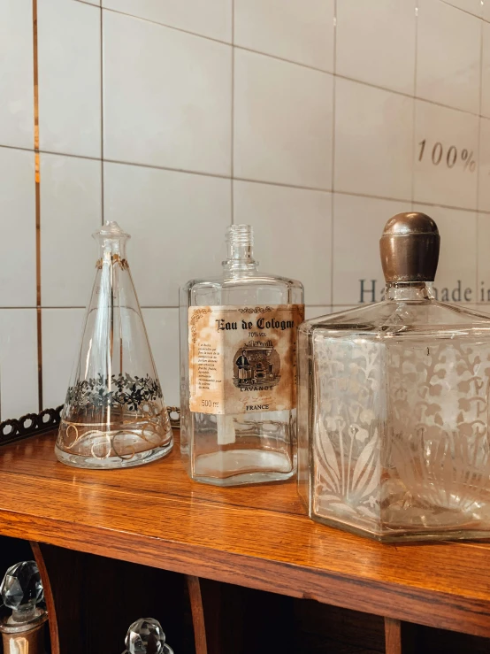 a couple of bottles sitting on top of a wooden shelf, trending on unsplash, renaissance, in style of chrome hearts, glass cover, 1900s picture, close-up product photo