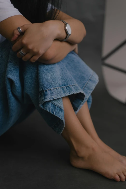 a woman sitting on the ground with her legs crossed, trending on unsplash, wearing denim, unclipped fingernails, low quality photo, loosely cropped