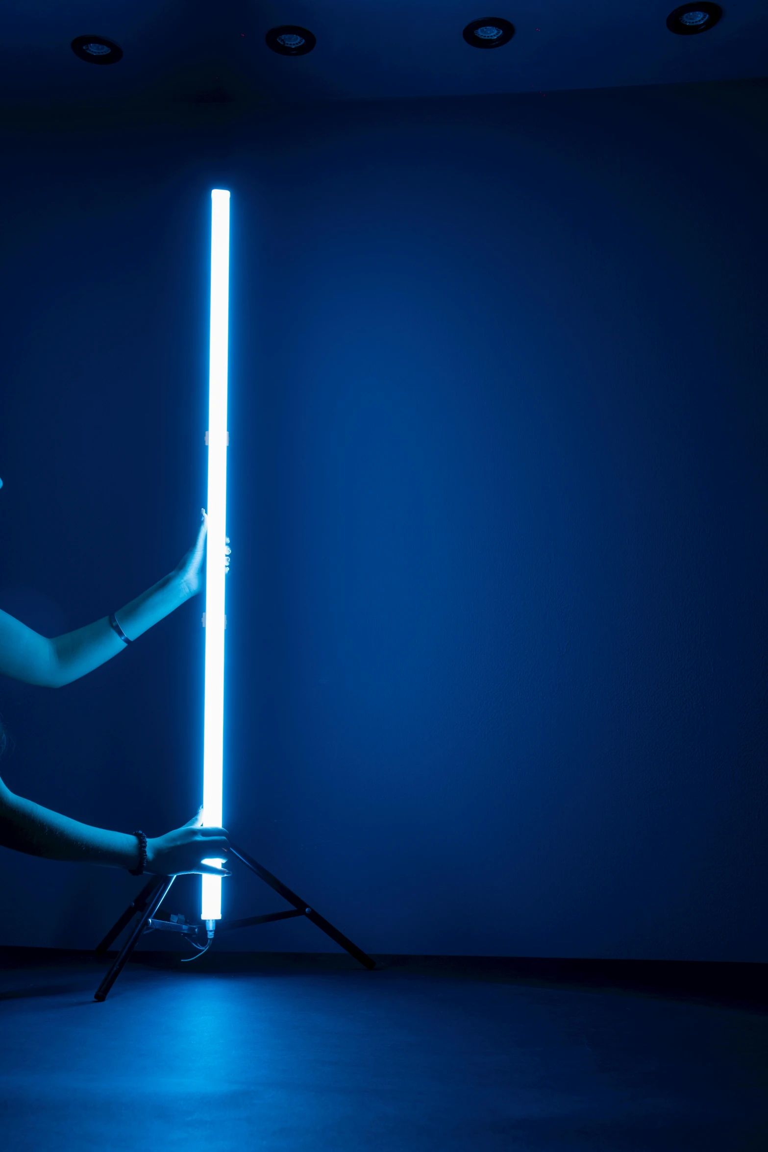 a man holding a light saber in a dark room, an album cover, by Ryan Pancoast, unsplash, light and space, pole dancing, bright blue future, emerging from her lamp, studio light