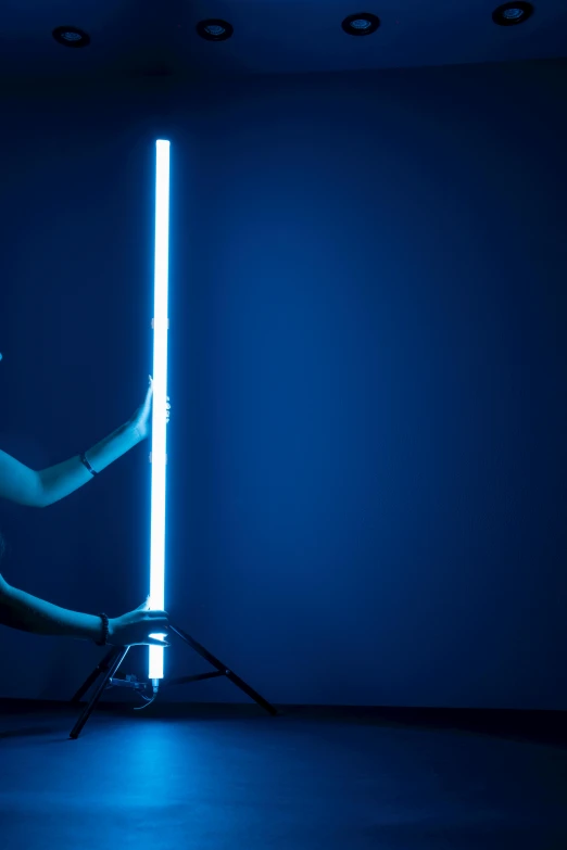 a man holding a light saber in a dark room, an album cover, by Ryan Pancoast, unsplash, light and space, pole dancing, bright blue future, emerging from her lamp, studio light