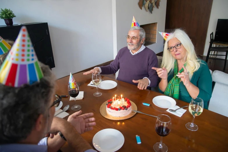 a group of people sitting around a table with a cake, profile image