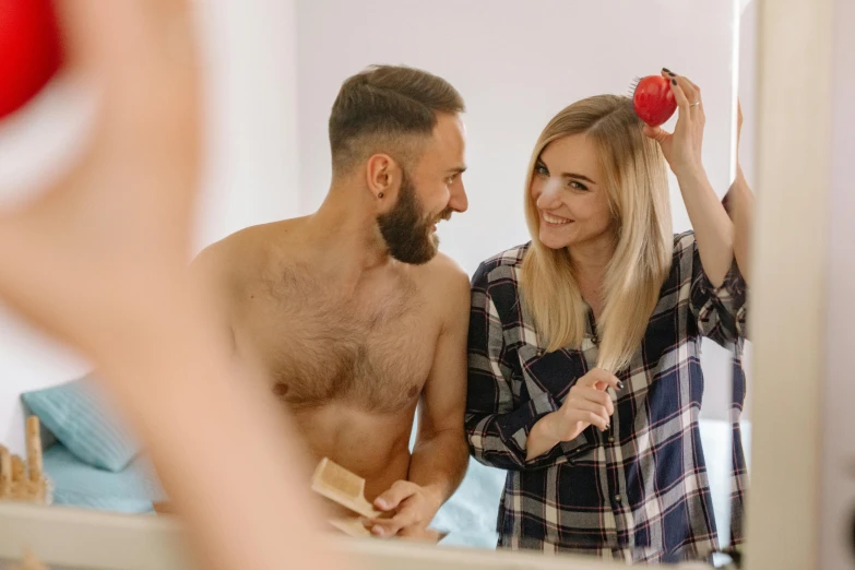 a man and a woman standing in front of a mirror, body hair, holding an apple, wearing a flannel shirt, paradise garden massage