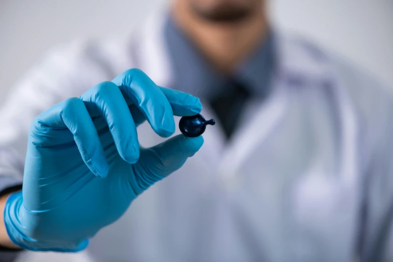 a man in a lab coat holding a piece of plastic, a microscopic photo, shutterstock, photorealism, gradient blue black, contracept, wearing a blue berries, speculum