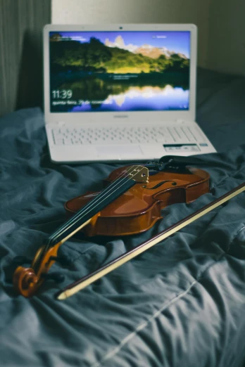 a violin sitting on top of a bed next to a laptop, playing, paul barson, laptops, complexly detailed