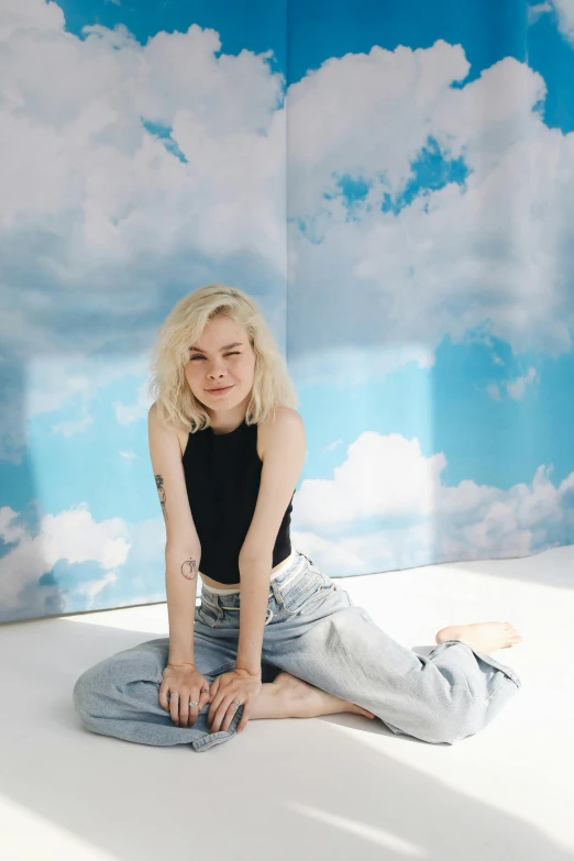 a woman sitting on the ground in front of a wall, an album cover, inspired by Elsa Bleda, trending on pexels, standing on a cloud, elle fanning, cumulus tattoos, sitting on top of a cryopod