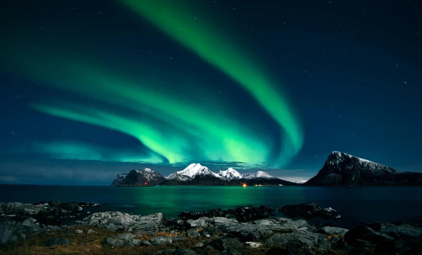 a large body of water with a mountain in the background, northern lights, waves of lights, balaskas, conde nast traveler photo