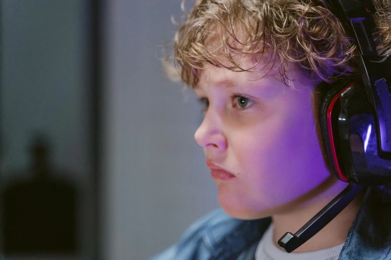 a young boy wearing headphones sitting in front of a computer, pexels, realism, ps5 cinematic screen capture, serious focussed look, in an call centre office, teenage girl