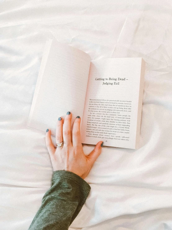 a person reading a book on a bed, by Grace Polit, trending on unsplash, diary on her hand, plain background, low quality photo, saying