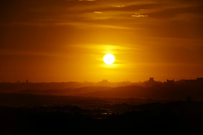 the sun is setting over a large body of water, a picture, pexels, romanticism, imperial city in the distance, digital yellow red sun, hazy, gold