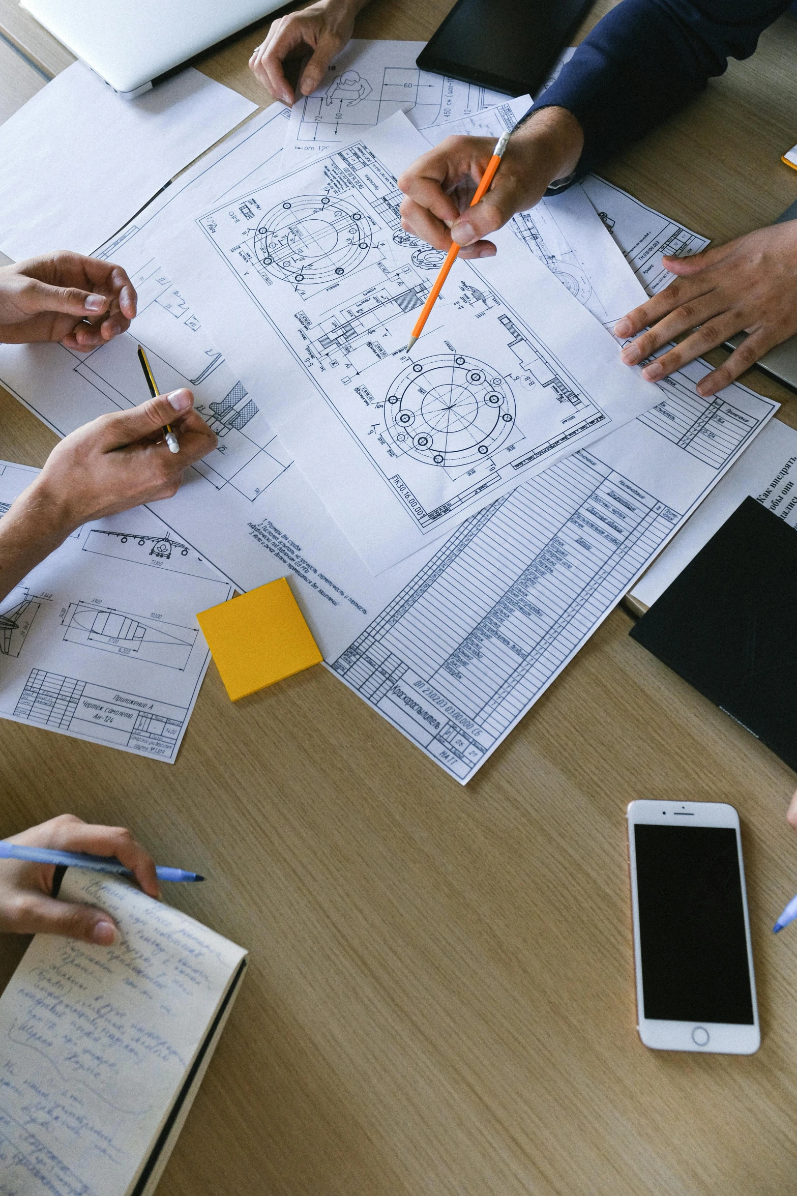 a group of people sitting around a wooden table, a cartoon, trending on unsplash, renaissance, engineering blueprints, formulas, a high angle shot, high quality photo