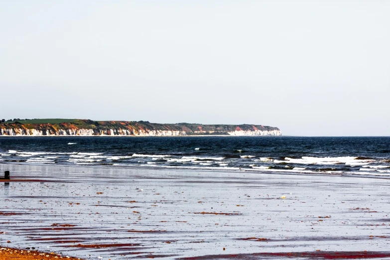 a man standing on top of a sandy beach next to the ocean, les nabis, white buildings with red roofs, craigville, nature photo