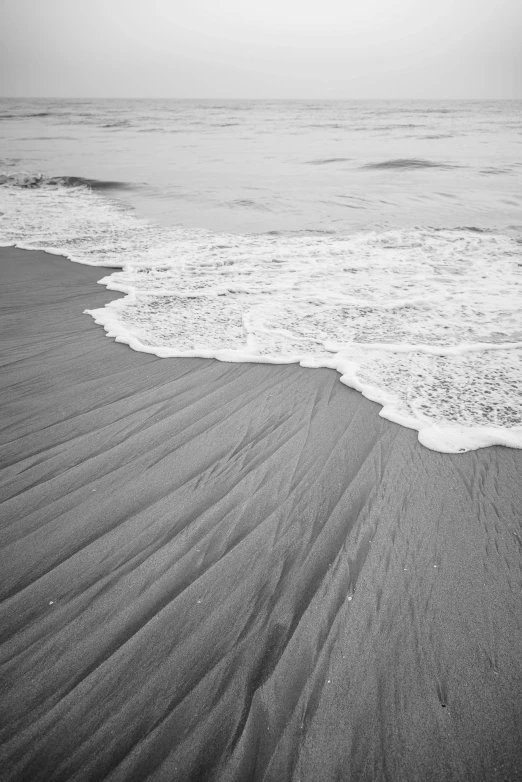 a black and white photo of the ocean, sand swirling, fineartamerica