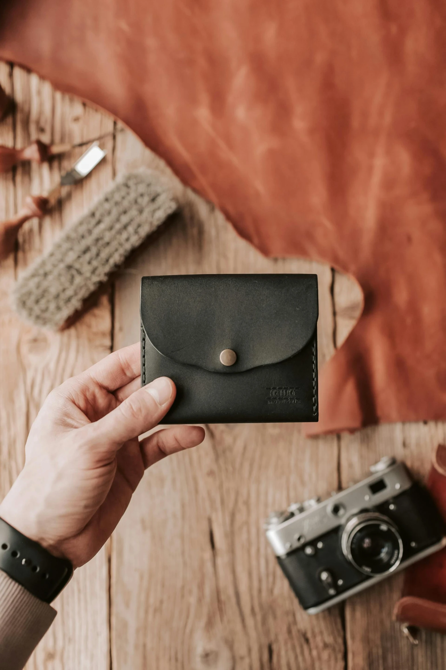 a person holding a wallet on top of a wooden table, inspired by Luděk Marold, unsplash contest winner, private press, ball shaped accordion sleeve, matte black, full front view, medium format film photography