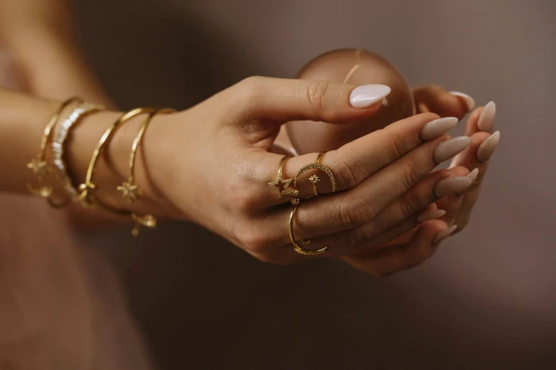 a close up of a person holding a cell phone, gold jewellery, armillary rings jewelry, ochre, bracelets