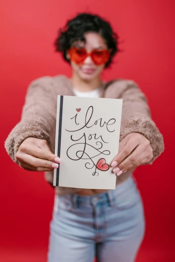 a woman holding a card that says i love you, an album cover, pexels, holding notebook, portrait n - 9, greeting card, y2k”
