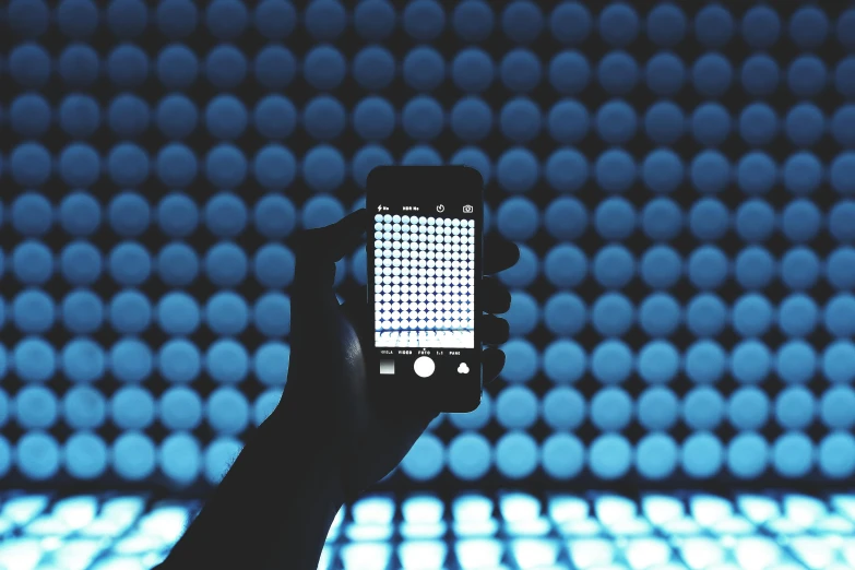 a person taking a picture with a cell phone, a hologram, by Carey Morris, trending on unsplash, interactive art, blue scales with white spots, ( ( stage lights ) ), made of dots, fill light. studio