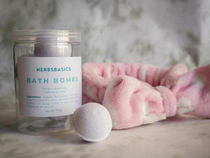 a jar of bath bombs next to a pink towel, by Ruth Abrahams, heroic, white robe, hgrenades, products shot