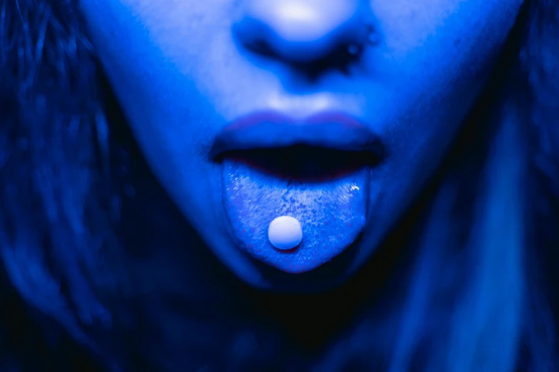 a close up of a person with a tongue, inspired by Elsa Bleda, unsplash, bauhaus, pills, blue bioluminescence, body modification, offering the viewer a pill