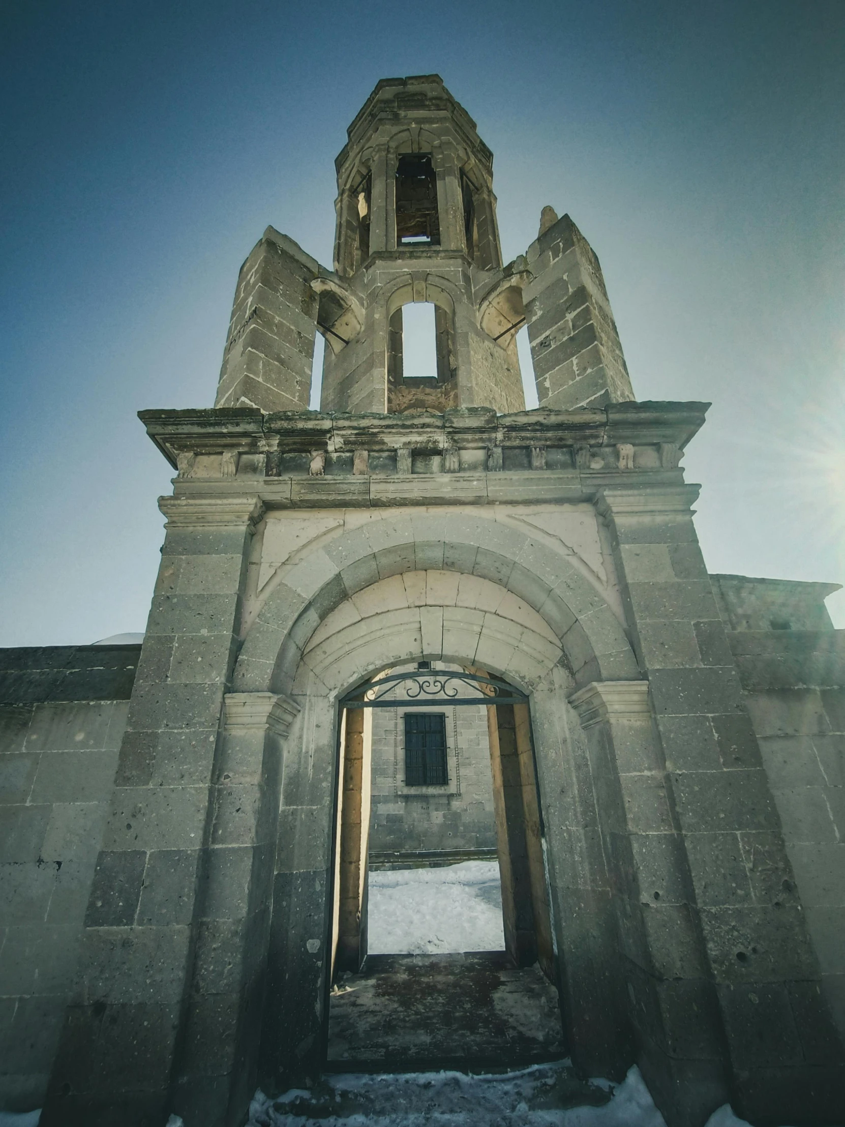 a large stone building with a clock tower, an album cover, pexels contest winner, romanesque, gate to hell, jerez, grey, sunlit