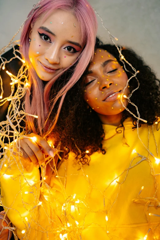 a couple of women standing next to each other, inspired by Ren Hang, trending on pexels, renaissance, fairy lights, pink and yellow, close - up studio photo, diverse