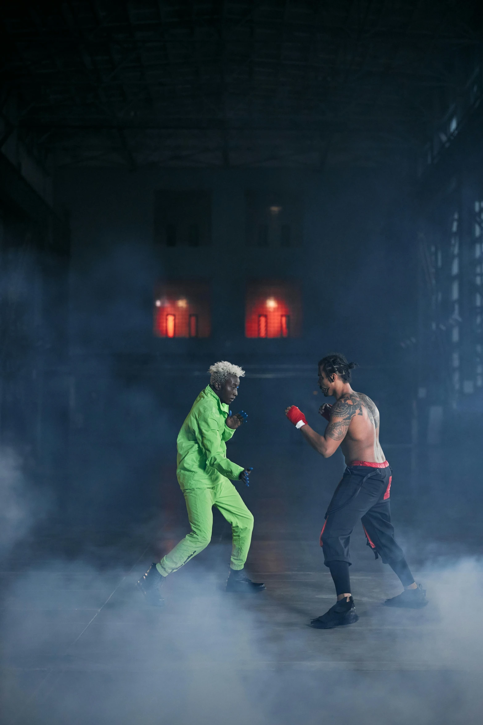 a couple of men standing next to each other on a stage, inspired by Daryush Shokof, pexels contest winner, conceptual art, green rubber suit godzilla, in a boxing ring, die antwoord music video, in a warehouse