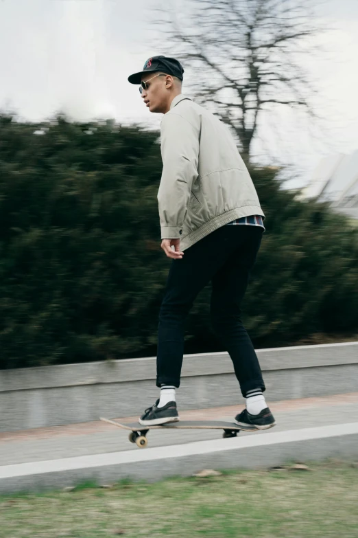 a man riding a skateboard down the side of a road, by Niko Henrichon, trending on unsplash, renaissance, grey jacket, plain background, wearing pants, south korean male