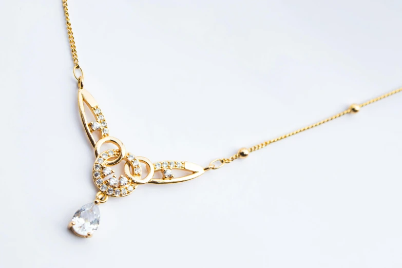 a close up of a necklace on a white surface, by Maeda Masao, trending on shutterstock, art nouveau, gilded gold and diamonds, simple white background, shot on sony a 7, high angle shot