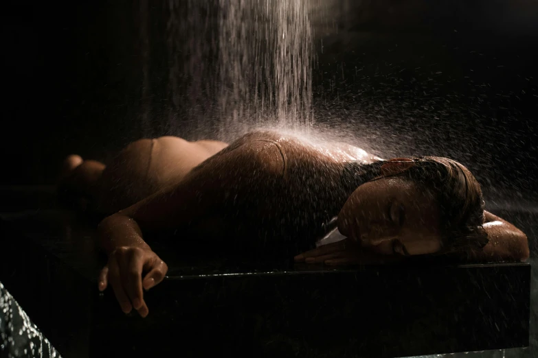 a woman laying down under a waterfall of water, inspired by Elsa Bleda, woman in a dark factory, taken with sony alpha 9, 8 k sensual lighting, under a shower