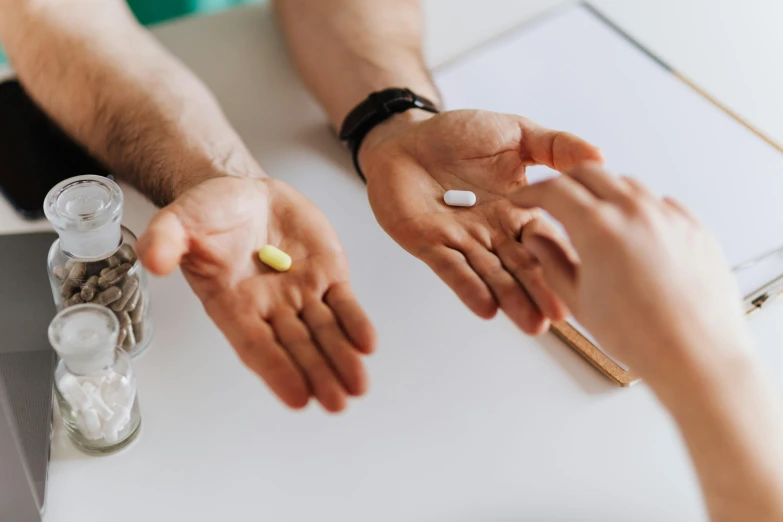 a couple of people that are sitting at a table, a picture, trending on pexels, offering the viewer a pill, natural hands and arms, medical photography, 30 year old man