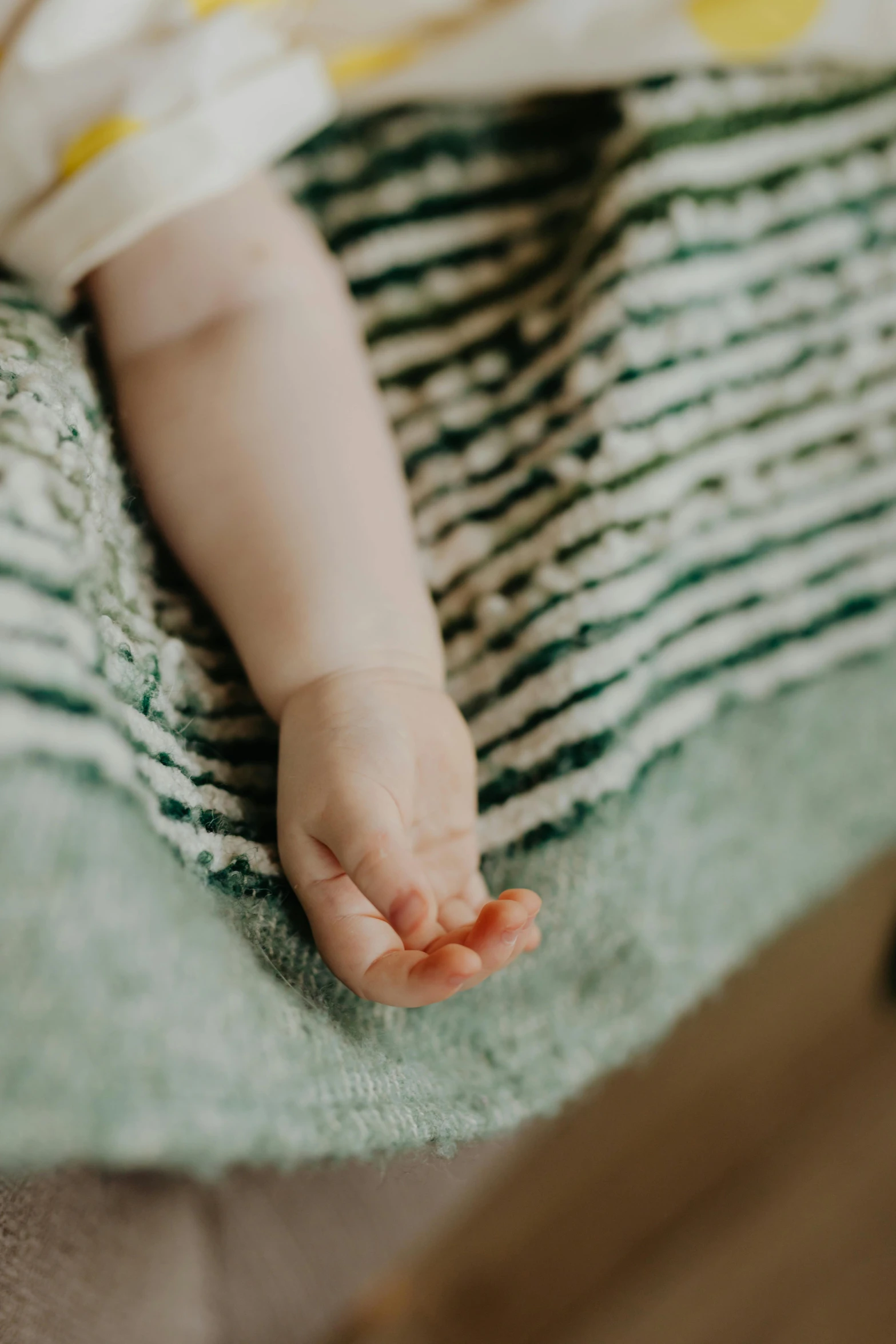 a close up of a baby's foot on a blanket, unsplash, green clothes, elegantly dressed, high resolution, indoor picture