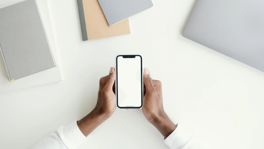 a close up of a person holding a cell phone, a picture, trending on pexels, computer art, on a white table, 9 9 designs, ( ( dark skin ) ), no - text no - logo