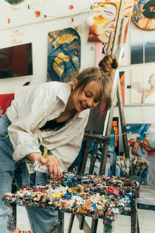 a woman working on a painting in an art studio, trending on pexels, process art, smiling playfully, artist wearing torn overalls, saturated pointillism, portrait of barbara palvin