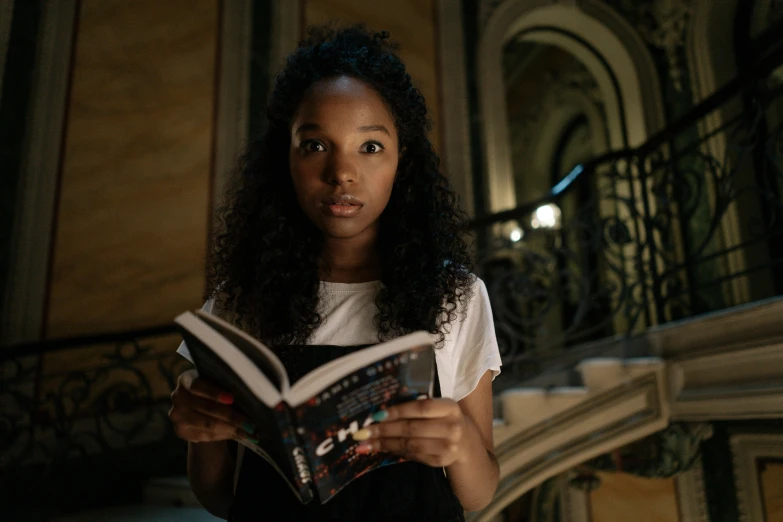 a woman reading a book in a building, a portrait, pexels contest winner, renaissance, black teenage girl, from netflix's arcane, beautiful stella maeve magician, looking straight to camera