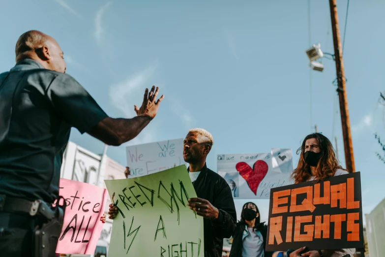 a group of people holding signs on a city street, by Julia Pishtar, trending on pexels, black arts movement, a photo of a man, bright sky, fight, california;
