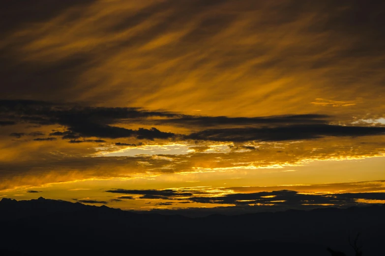 a silhouette of a person flying a kite at sunset, by Peter Churcher, pexels contest winner, romanticism, yellow clouds, distant mountains lights photo, sunset panorama, brown