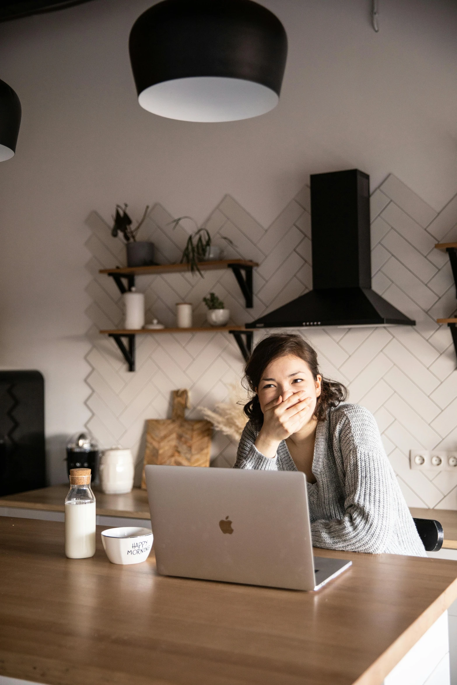 a woman sitting at a kitchen counter with a laptop, pexels contest winner, portrait of modern darna, grey, cozy environment, bo chen