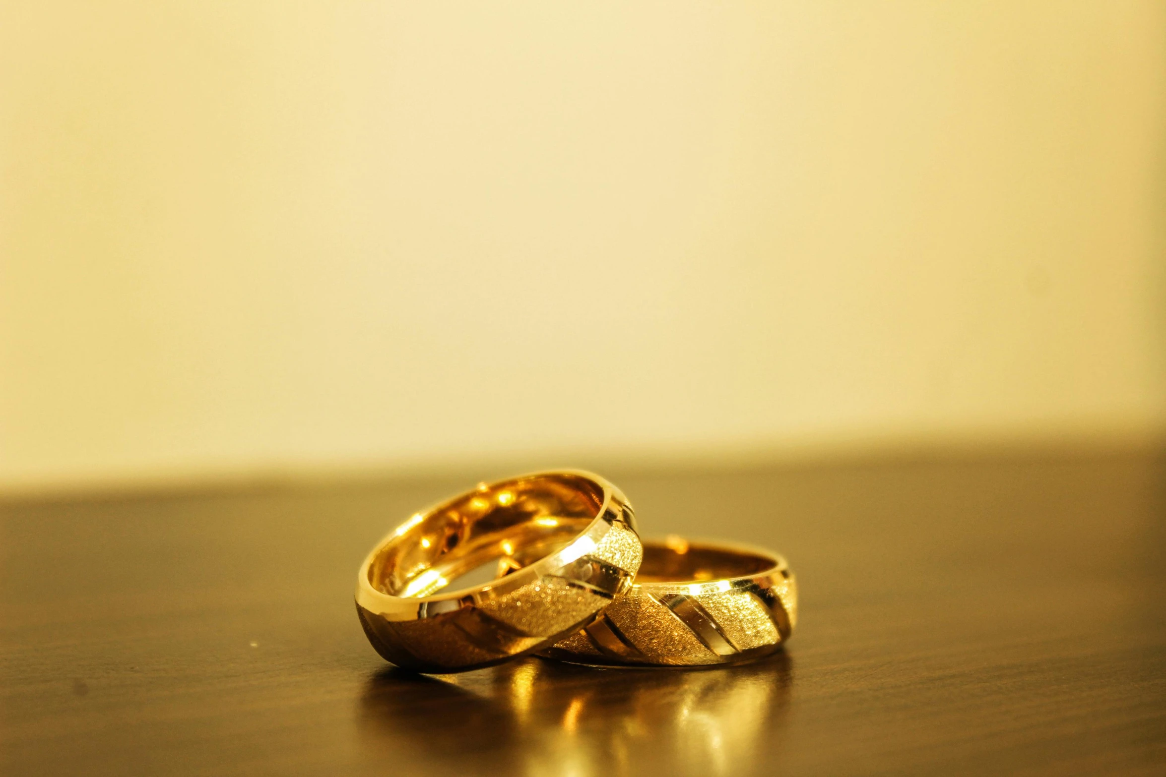 two wedding rings sitting on top of a wooden table, pexels, made of gold, shot on sony alpha dslr-a300, gold black, unedited