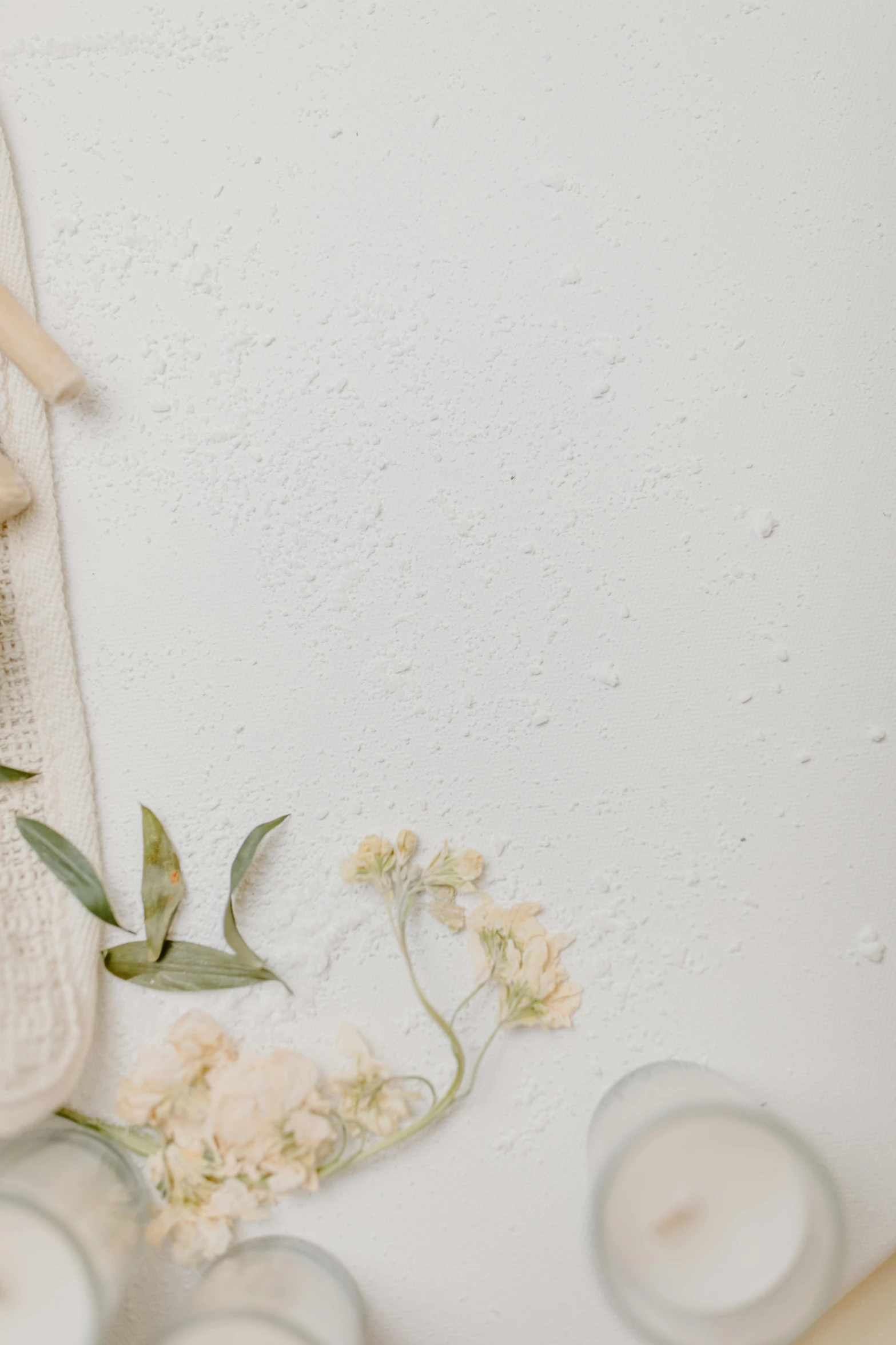 a towel sitting on top of a table next to candles, trending on unsplash, conceptual art, pressed flowers, white paper background, flour dust spray, floral wallpaper