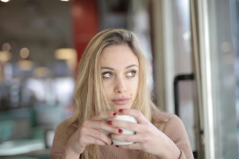 a woman sitting at a table with a cup of coffee, pexels contest winner, realism, blonde hair and large eyes, thoughtful ), mid 2 0's female, teenage girl