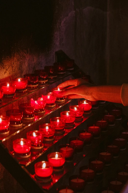 a person lighting candles in a dark room, ossuary, small red lights, in australia, profile image