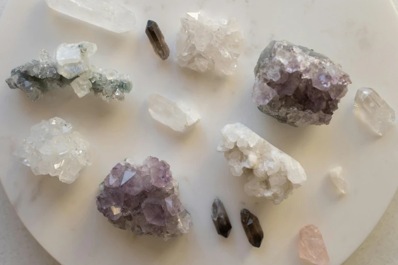 a bunch of crystals sitting on top of a white plate, by Winona Nelson, trending on pexels, white and purple, rock and dust, miniature product photo, grey