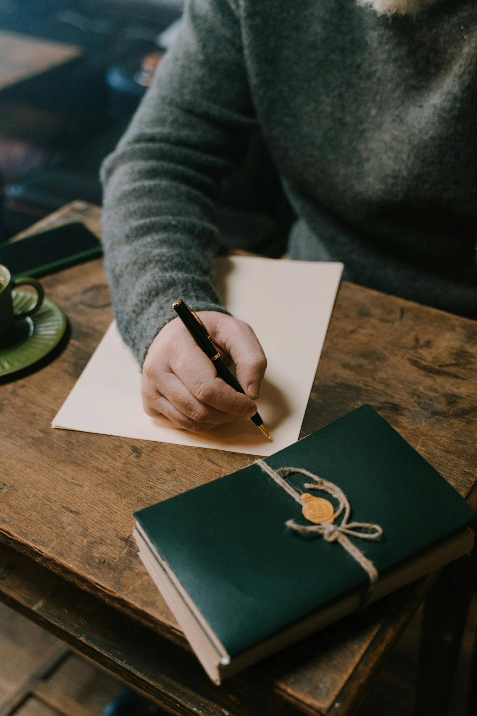 a person sitting at a table writing on a piece of paper, crafts and souvenirs, very aesthetically pleasing, post graduate, poetry