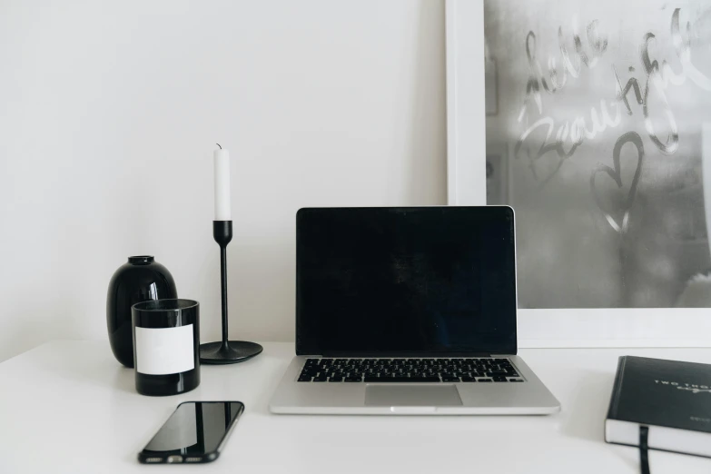 a laptop computer sitting on top of a white desk, a black and white photo, by Carey Morris, trending on pexels, minimalism, exquisite black accessories, in a white room, on a canva, portrait of small