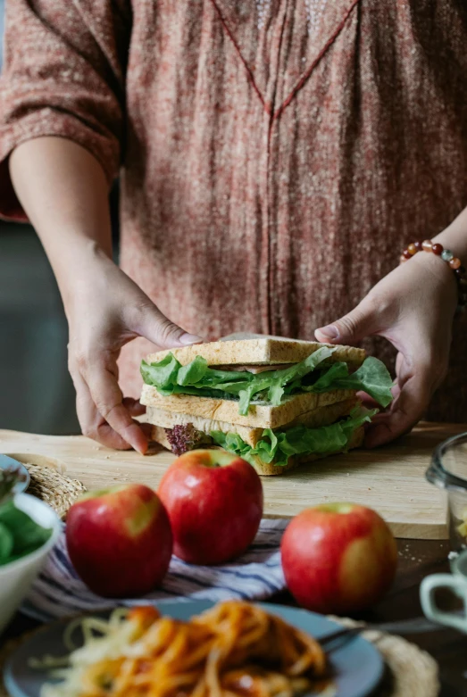 a woman preparing a sandwich on a cutting board, by Julia Pishtar, apple, uncrop, tall, 4l