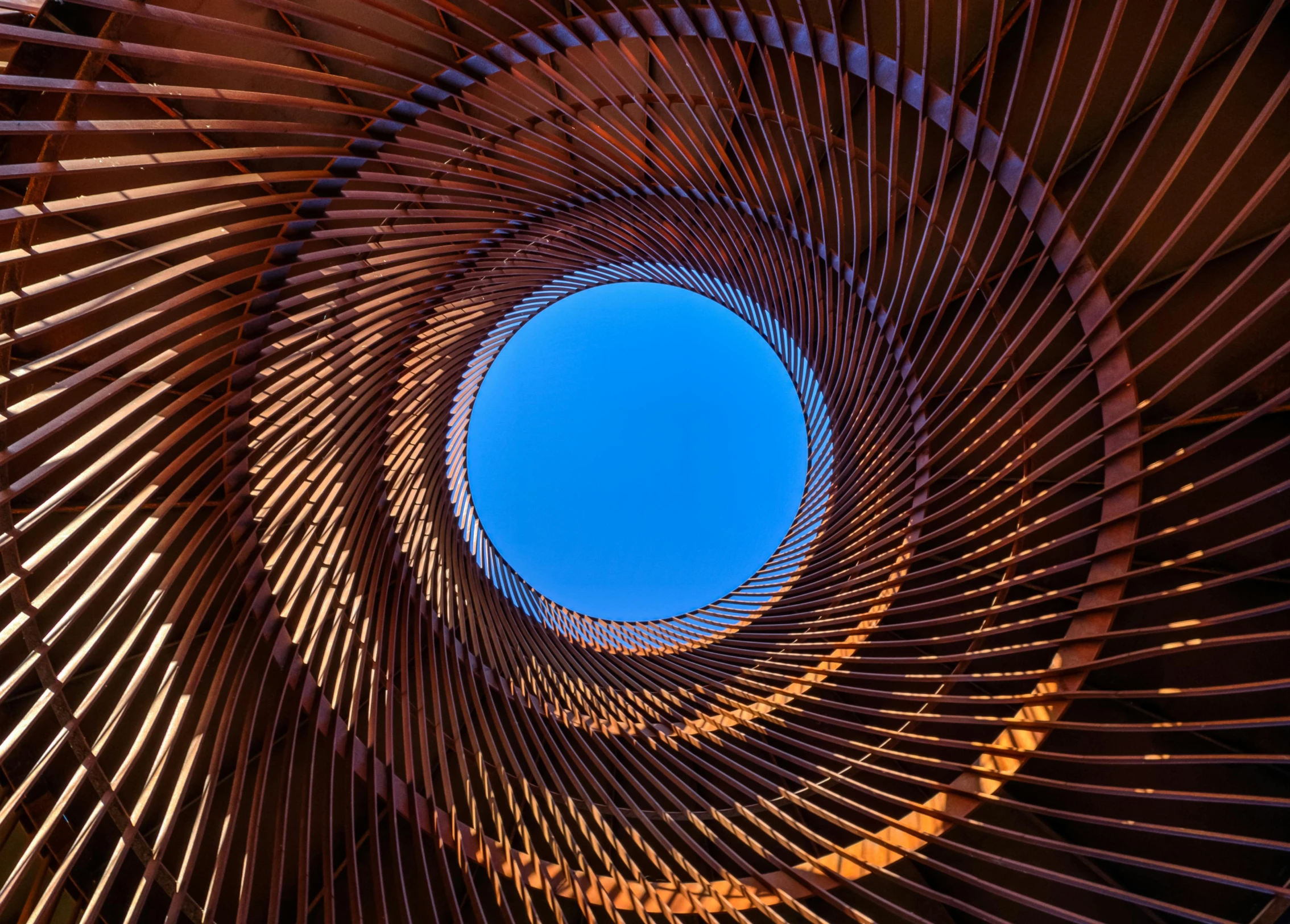 a spiral wooden structure with a blue sky in the background, inspired by Anish Kapoor, unsplash contest winner, intricate copper details, behance lemanoosh, intricate illuminated lines, geometrically realistic