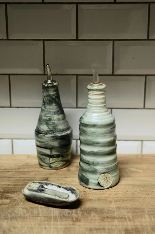 a couple of vases sitting on top of a wooden table, olive oil, marbled swirls, bespoke, bottle